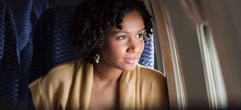 Use your American Express Card American Express Cardmember on a plane staring out of the window