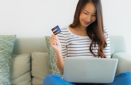 woman using a credit card to save on online shopping How to Stay for Free with a Hotel Credit Card