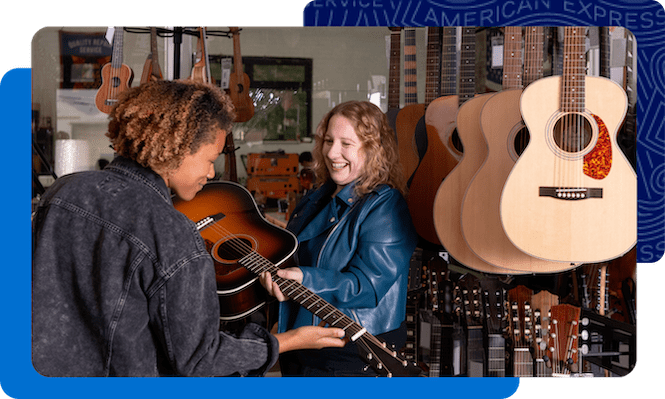 Guitar store owner showing a guitar to a customer.